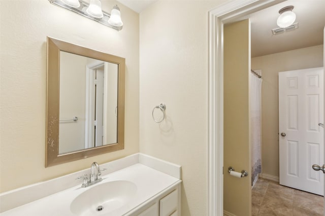 bathroom with tile patterned flooring, vanity, and walk in shower