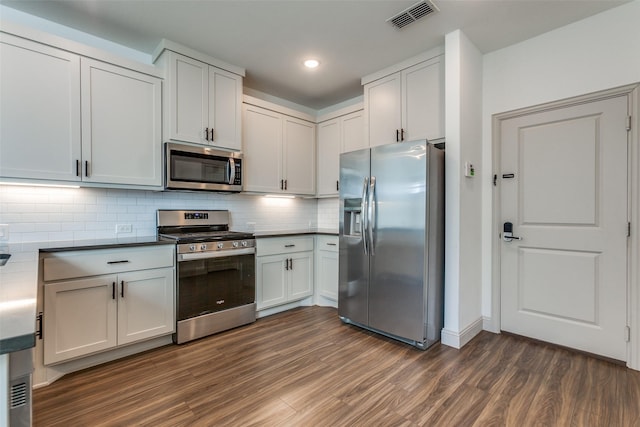 kitchen with stainless steel appliances, white cabinetry, and dark hardwood / wood-style floors