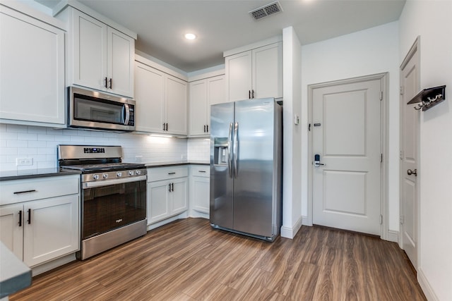 kitchen featuring decorative backsplash, white cabinets, and stainless steel appliances