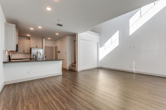 kitchen with backsplash, light hardwood / wood-style flooring, white cabinetry, and stainless steel appliances