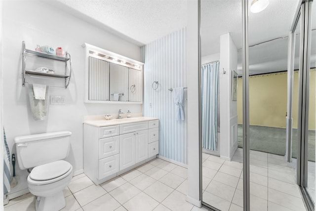 bathroom featuring a textured ceiling, toilet, vanity, and tile patterned flooring