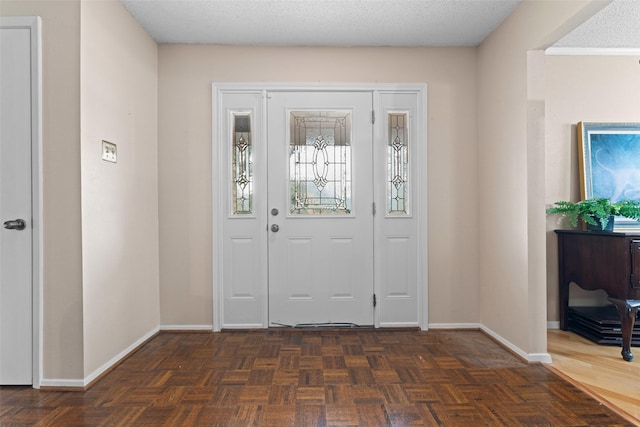 entryway with dark parquet floors and a textured ceiling