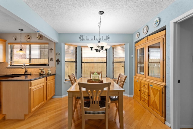 dining room featuring sink, a chandelier, light hardwood / wood-style flooring, and a textured ceiling