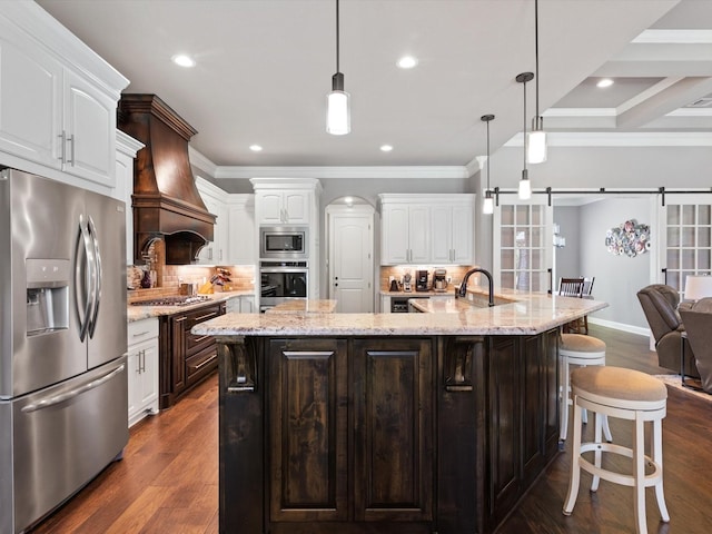 kitchen featuring decorative backsplash, white cabinets, appliances with stainless steel finishes, and a large island