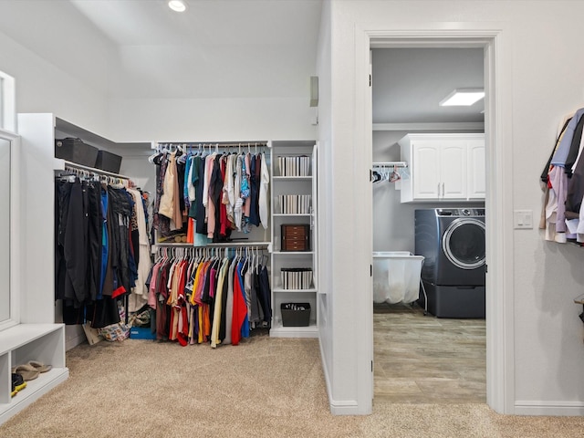 spacious closet with washer / clothes dryer and light carpet