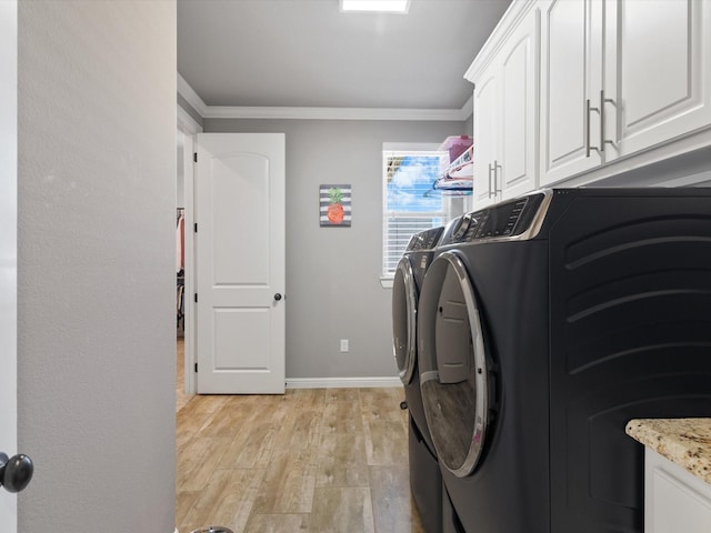 clothes washing area featuring crown molding, cabinets, light wood-type flooring, and washer and clothes dryer