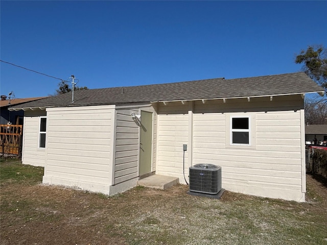 rear view of house featuring cooling unit and a lawn