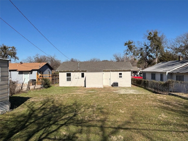 rear view of property with central AC and a lawn