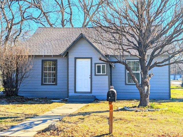 view of front facade with a shingled roof, a front yard, and entry steps