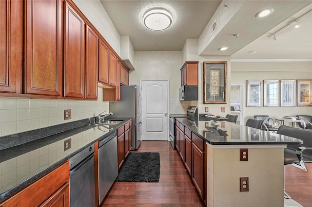 kitchen with sink, appliances with stainless steel finishes, dark hardwood / wood-style flooring, and track lighting