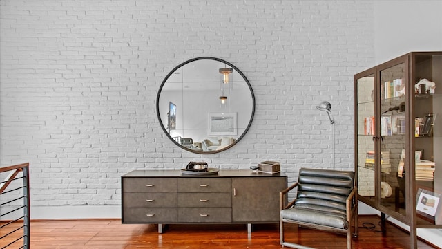 sitting room featuring hardwood / wood-style floors and brick wall