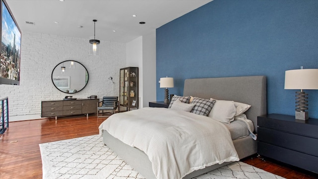 bedroom featuring hardwood / wood-style flooring and brick wall