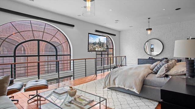 bedroom with hardwood / wood-style flooring and brick wall