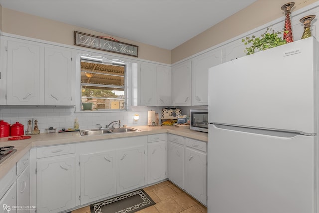 kitchen with sink, white cabinets, white fridge, and tasteful backsplash