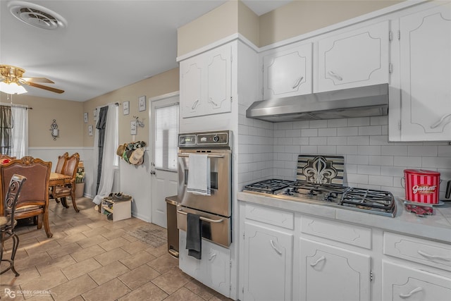 kitchen featuring backsplash, white cabinets, range hood, and appliances with stainless steel finishes