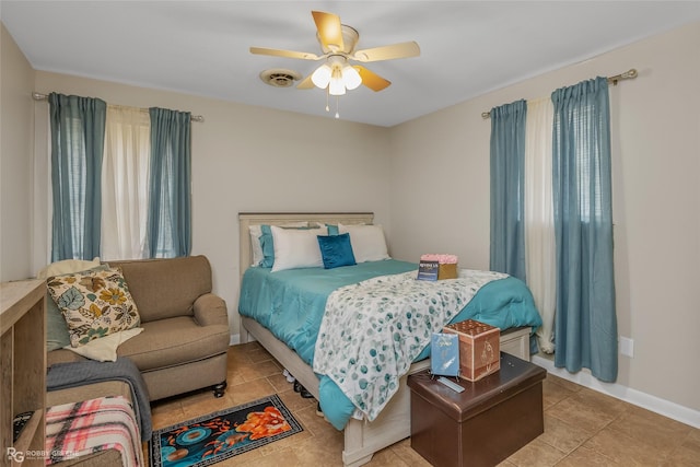 tiled bedroom with ceiling fan and multiple windows