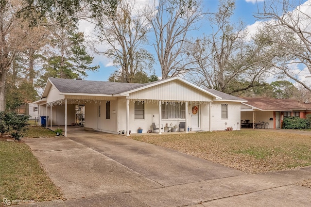 ranch-style house featuring covered porch, a front yard, and a carport