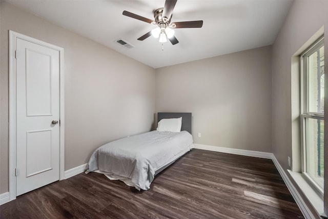 bedroom featuring multiple windows, dark wood-type flooring, and ceiling fan