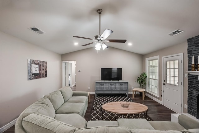 living room featuring ceiling fan, dark hardwood / wood-style flooring, a stone fireplace, and vaulted ceiling