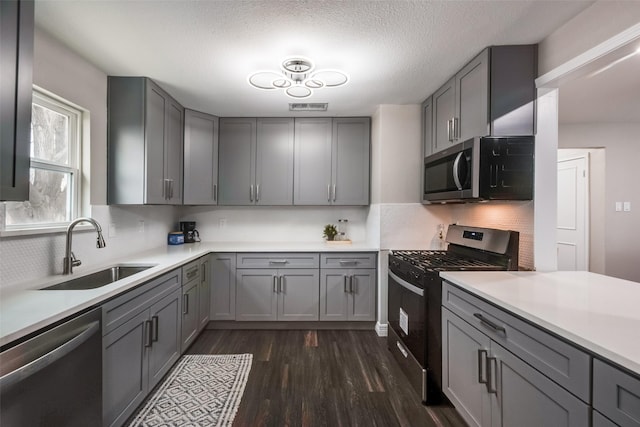 kitchen featuring sink, backsplash, appliances with stainless steel finishes, and gray cabinetry