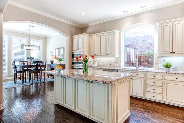 kitchen featuring decorative light fixtures, light stone countertops, cream cabinetry, and a kitchen island