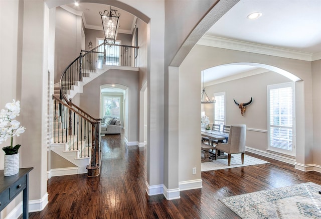 entryway with dark hardwood / wood-style floors, ornamental molding, and an inviting chandelier