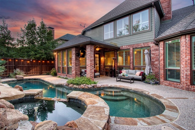 pool at dusk featuring an outdoor living space, an in ground hot tub, and a patio area