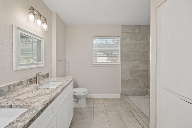 bathroom featuring plenty of natural light, toilet, tile patterned floors, and vanity