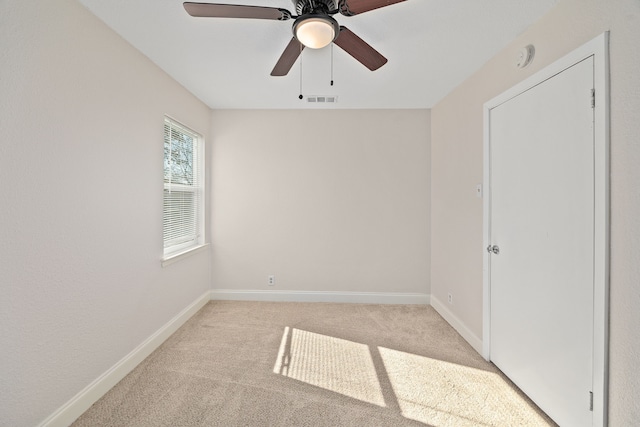 spare room with ceiling fan and light colored carpet