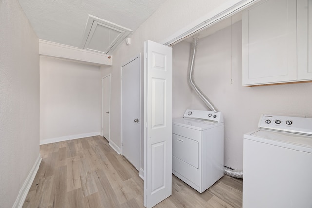 laundry area featuring light wood-type flooring, a textured ceiling, and washer and dryer