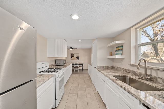 kitchen featuring sink, light stone countertops, white cabinets, and appliances with stainless steel finishes