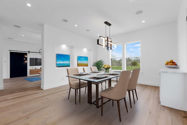 dining area featuring an inviting chandelier, light hardwood / wood-style flooring, and a barn door