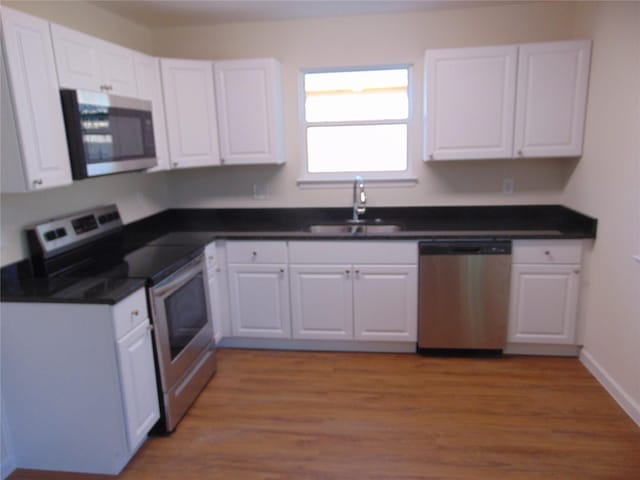 kitchen featuring sink, light wood-type flooring, white cabinetry, and appliances with stainless steel finishes