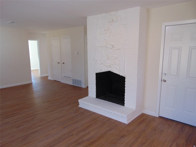 unfurnished living room featuring a fireplace and dark wood-type flooring