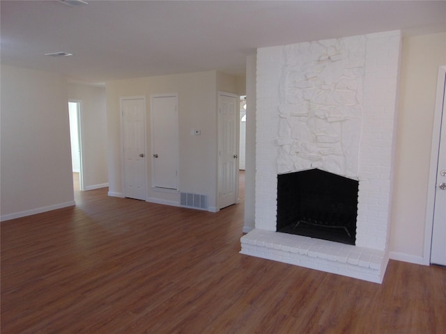 unfurnished living room with dark hardwood / wood-style floors and a brick fireplace