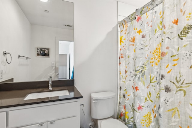 bathroom with toilet, vanity, and walk in shower