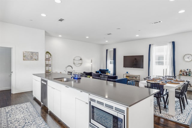 kitchen featuring white cabinetry, sink, dark hardwood / wood-style flooring, an island with sink, and stainless steel appliances