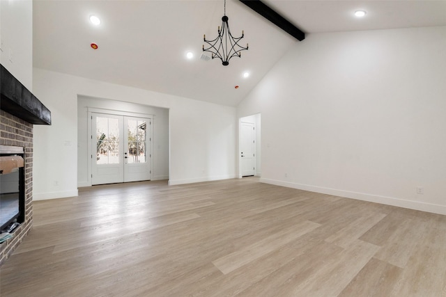 unfurnished living room with light wood-type flooring, a brick fireplace, high vaulted ceiling, a notable chandelier, and beamed ceiling