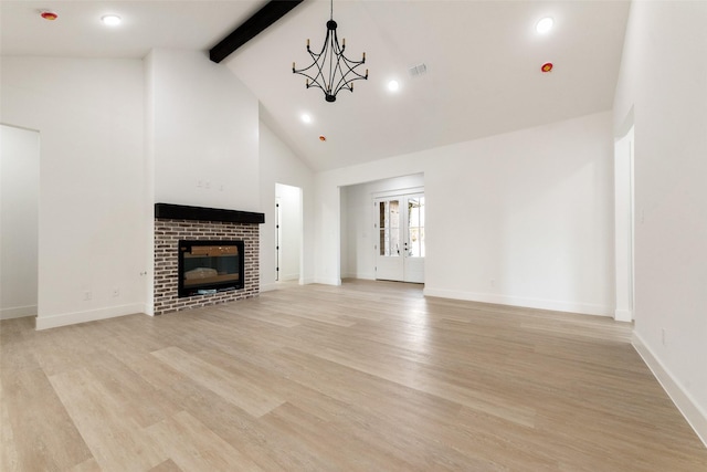 unfurnished living room featuring beamed ceiling, a chandelier, a brick fireplace, high vaulted ceiling, and light hardwood / wood-style flooring