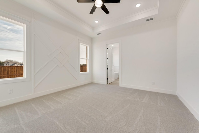 empty room featuring ceiling fan, light colored carpet, and a raised ceiling