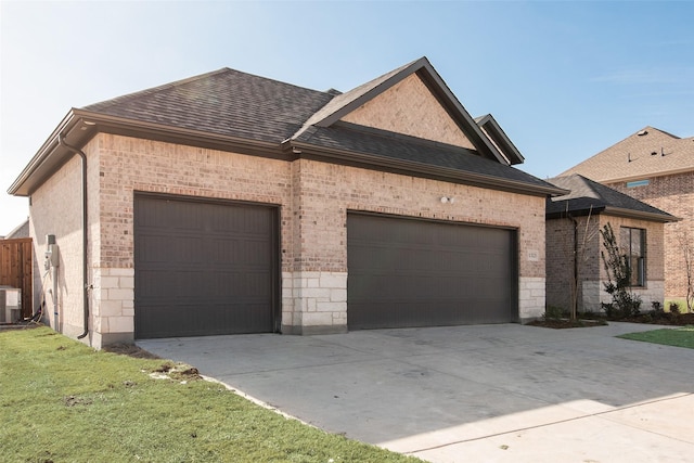 view of front of property with a front yard, central AC unit, and a garage