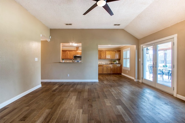 unfurnished living room with a textured ceiling, vaulted ceiling, ceiling fan, and dark hardwood / wood-style flooring