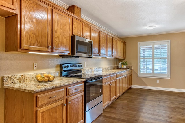 kitchen featuring crown molding, light stone countertops, a textured ceiling, dark hardwood / wood-style flooring, and stainless steel appliances