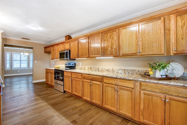 kitchen featuring light wood-type flooring, stainless steel appliances, ornamental molding, and light stone countertops