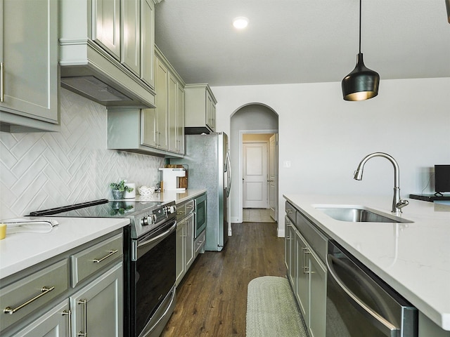 kitchen with pendant lighting, dark hardwood / wood-style flooring, sink, backsplash, and stainless steel appliances