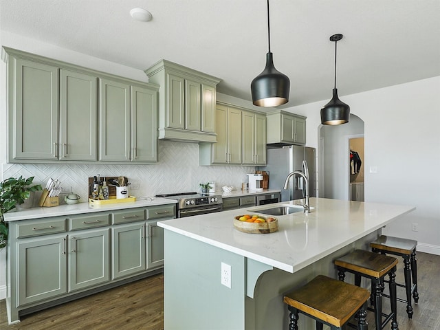 kitchen featuring appliances with stainless steel finishes, hanging light fixtures, sink, an island with sink, and a breakfast bar area