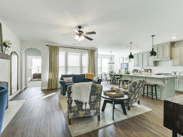 living room with ceiling fan, sink, a brick fireplace, and dark hardwood / wood-style flooring