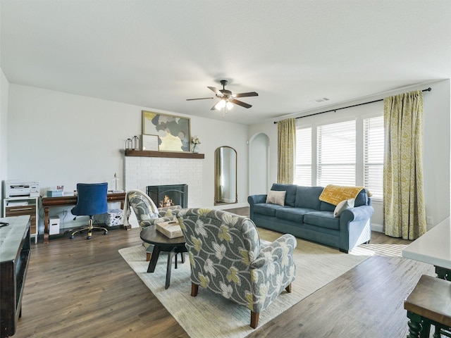 living room with ceiling fan, a brick fireplace, and hardwood / wood-style floors