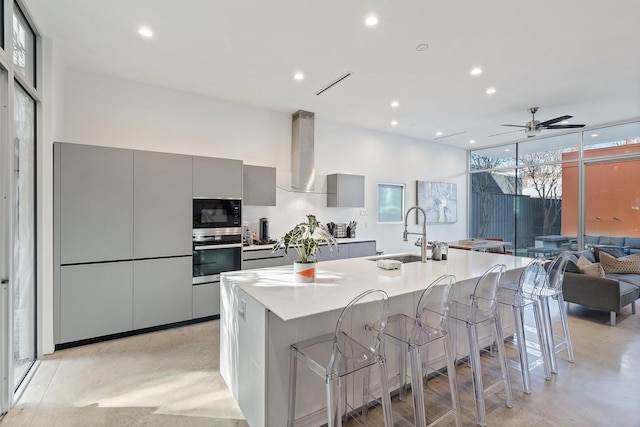 kitchen with a spacious island, a breakfast bar, sink, gray cabinets, and oven