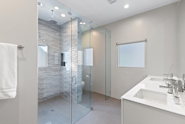 bathroom with vanity, a shower with door, and toilet